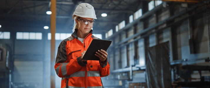 Female worker in a hard hat on job site documents work on tablet Female worker in a hard hat on job site documents work on tablet